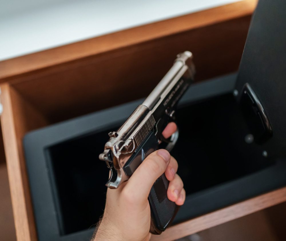 Gun-Safe Man takes the weapon from the safe.